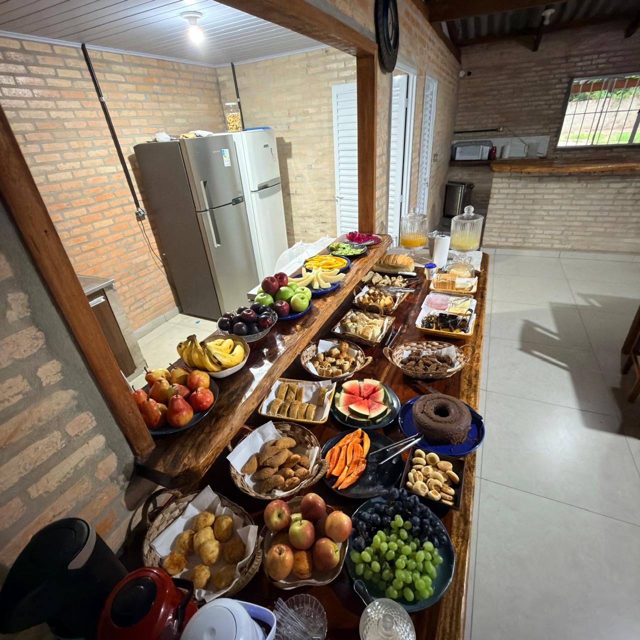 Long wooden table with a breakfast spread of fruit, breads and cakes