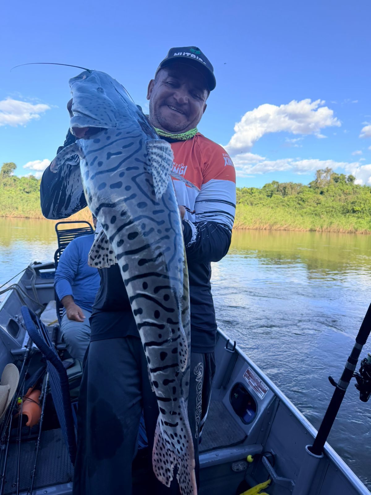 Angler holding a tiger-striped cachara on a boat on the river