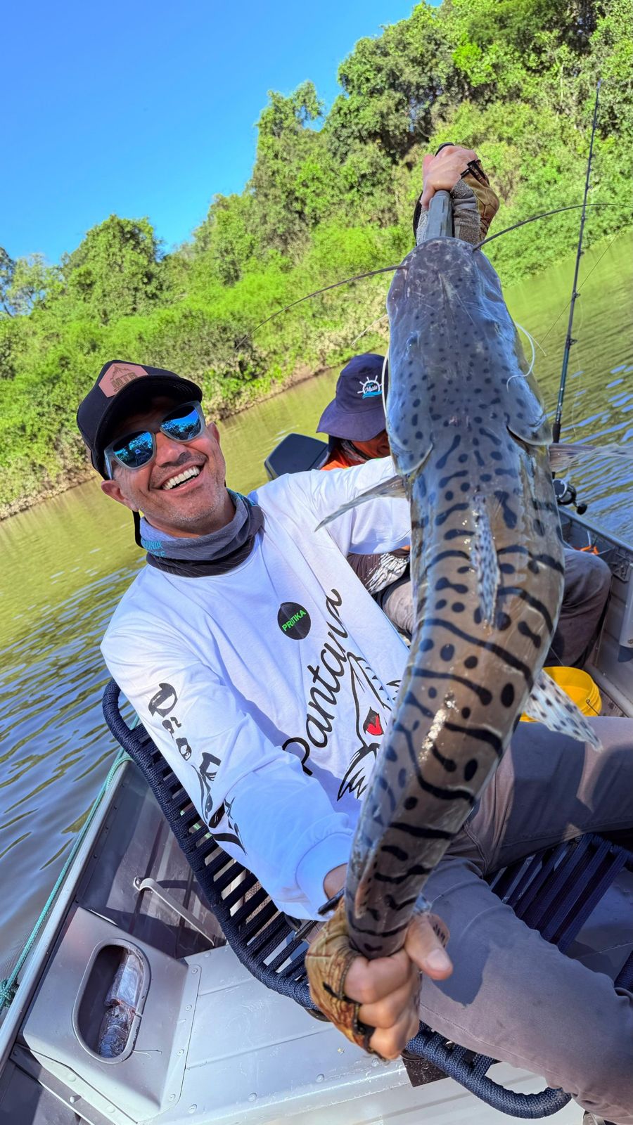 Smiling angler on a boat holding a spotted cachara catfish