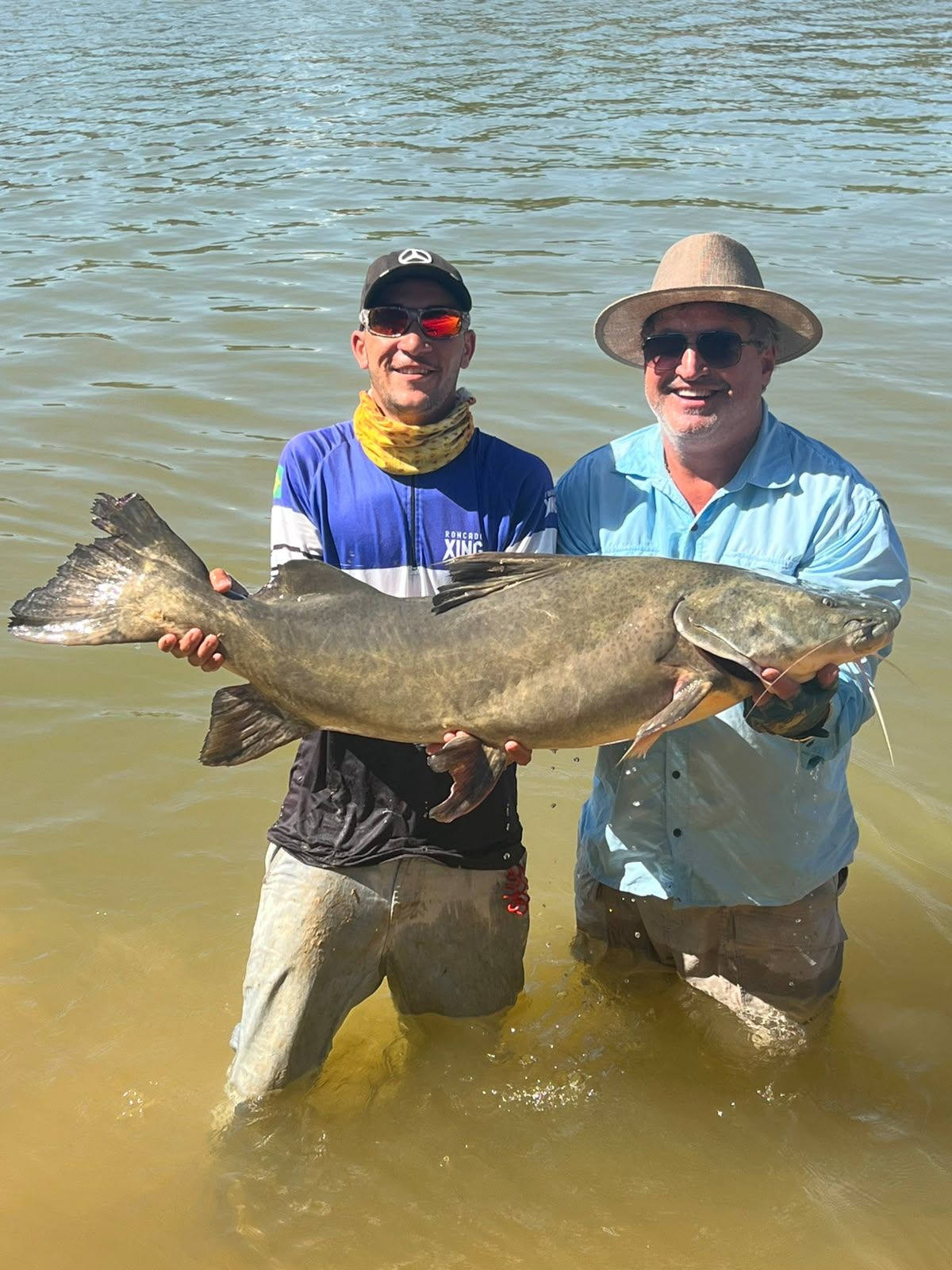 Guide and angler standing in the river holding a giant jaú