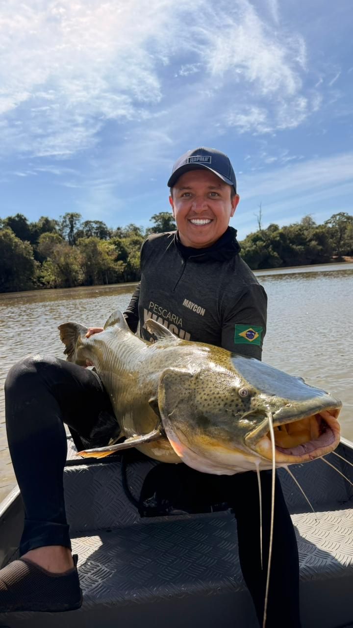 Angler on a boat holding a jaú with its mouth open