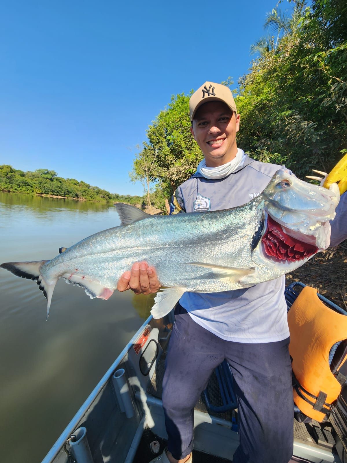 Angler on a boat holding a silver payara with long fangs